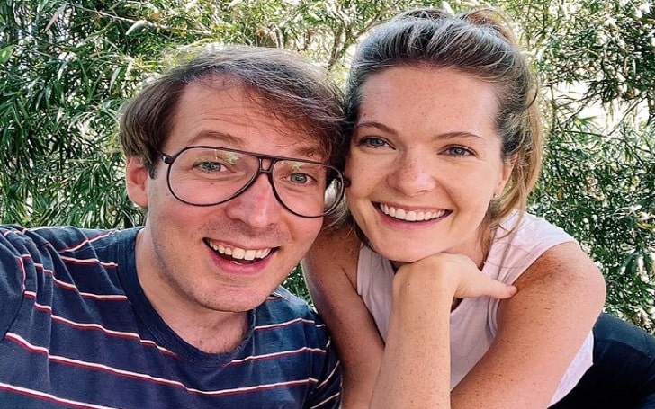 Olli Haaskivi smiling in a white-red lined blue t-shirt with his girlfriend in a light pink sleeveless.